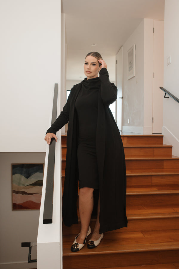 Woman in a black outfit standing on wooden stairs in a home setting