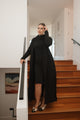 Woman in a black outfit standing on wooden stairs in a home setting