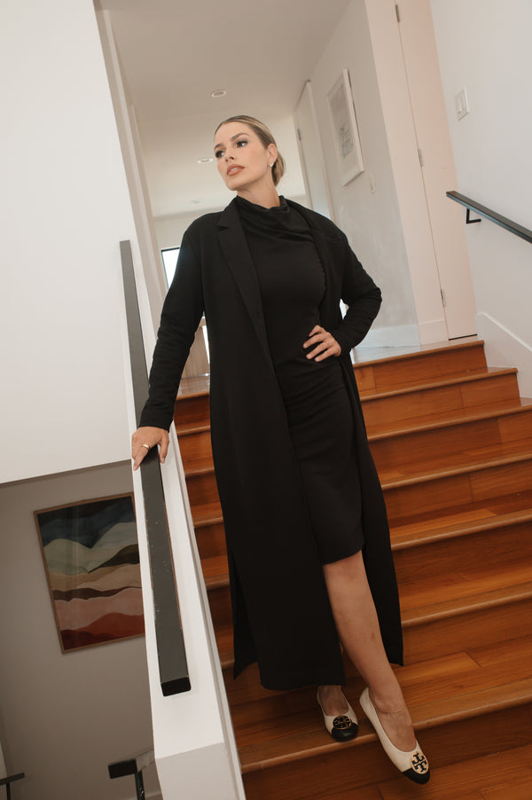Woman in a black outfit standing on a staircase indoors