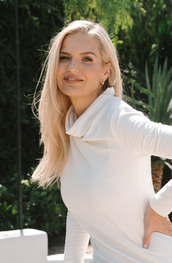 Woman in a white dress smiles at the camera