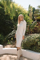 Woman in a white dress standing in a garden with greenery
