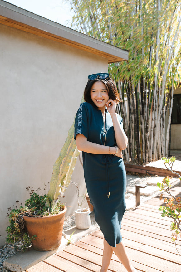 woman wearing long navy blue dress with gold zipper