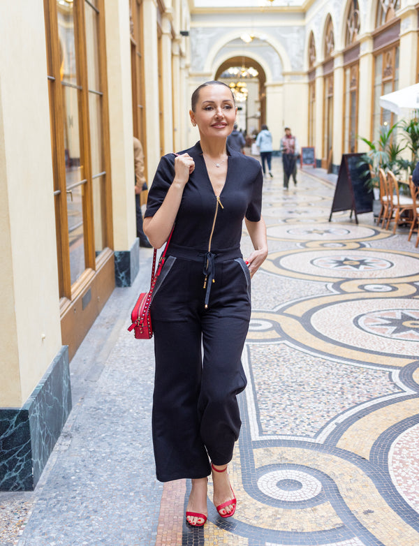 woman wearing black shirt with gold zipper, and black pants