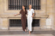 two women wearing white shirt with gold zipper and white pants, the other wearing brown shirt with gold zipper and brown pants
