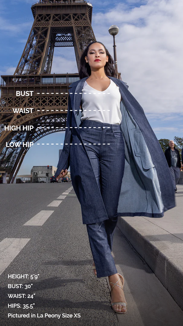woman wearing white tank top, with blue skirt with frills at bottom, and blue overcoat, with measurements