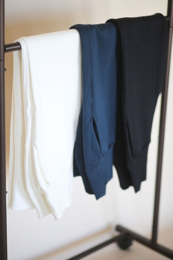 three stretch pants on a rack in blue black and white