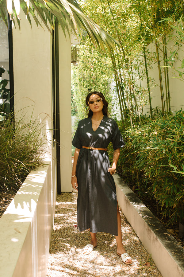 Woman in an indigo dress standing in a garden with bamboo and plants.