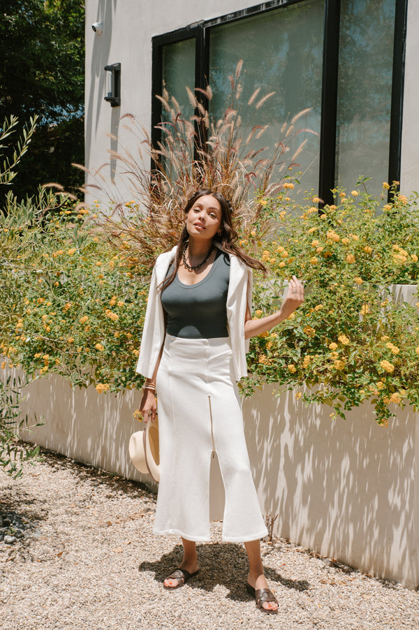 Woman standing outdoors with flowers and plants around her