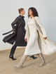 two women, one wearing long black dress with black leather overcoat, and the other wearing long white dress with white overcoat