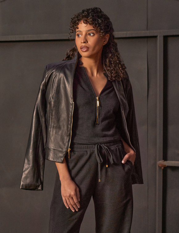 woman wearing black shirt with gold zipper, black pants, and denim jacket hanging on shoulders