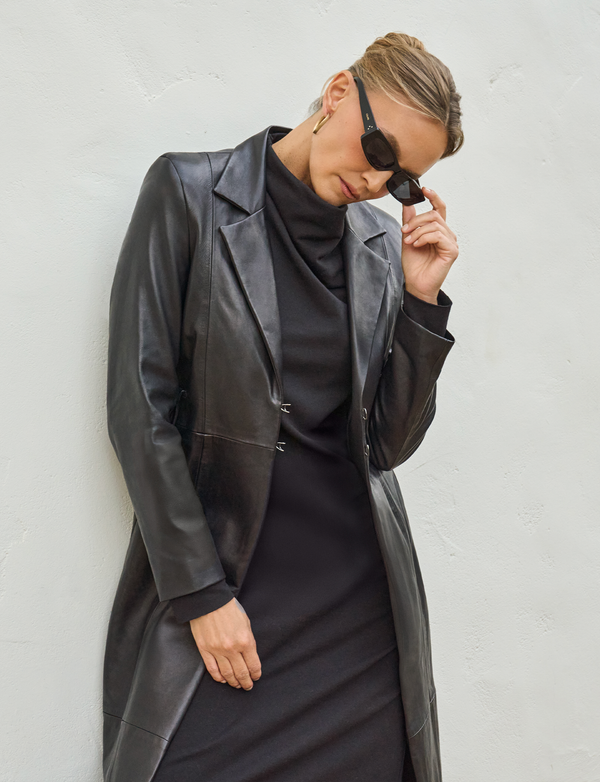 woman wearing long black dress with black leather overcoat with black glasses