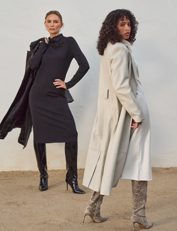 two women, one wearing long black dress with black leather overcoat, and the other wearing long white dress with white overcoat