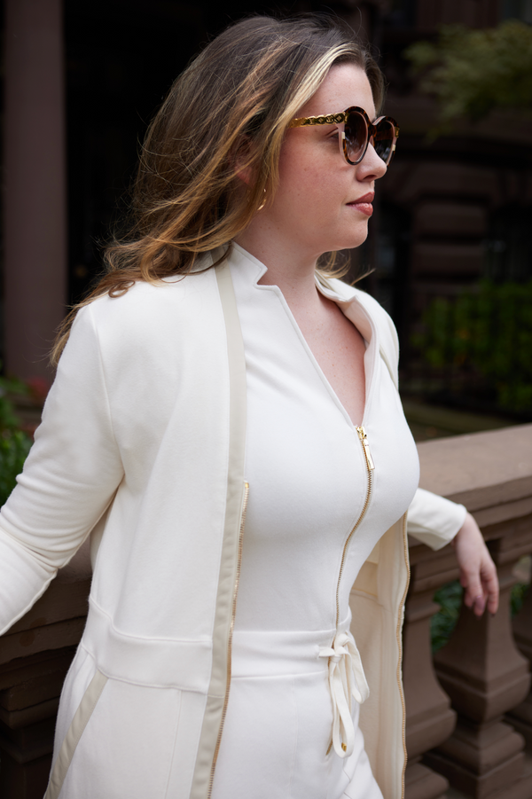 woman wearing white shirt with gold zipper, white pants and white overcoat