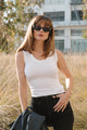 woman wearing white tank top with blue pants and black sunglasses