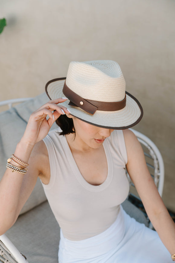 woman wearing tan tank top, long white skirt and tan fedora