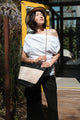 woman wearing white shirt with tan bag over the shoulder