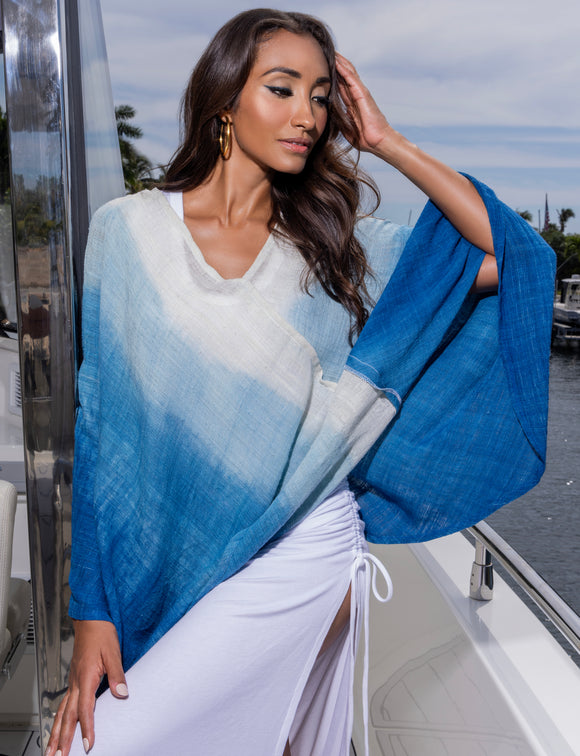 woman wearing blue and white poncho and white dress underneath