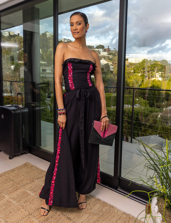 woman wearing black dress with red floral accents holding black and red handbag