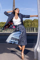 woman wearing white tank top, navy blue skirt with blue frilled designed inside of skirt, along with navy blue overcoat