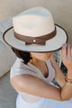 woman wearing long white dress with tan fedora holding