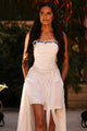 woman wearing white tube top with light blue accents, and white skirt with cutout area below the knees