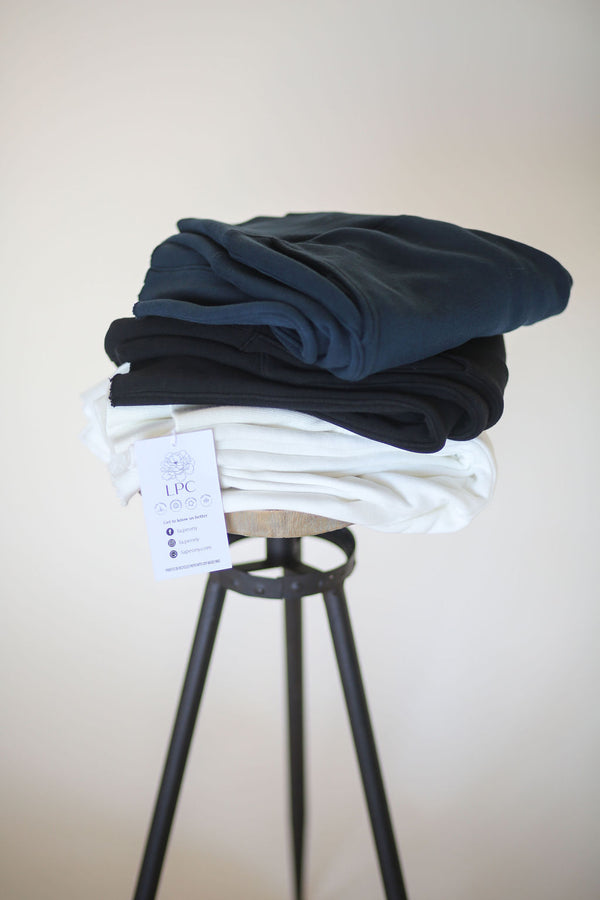 three women's stretch pants folded on a stool in white black and blue