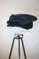 three women's stretch pants folded on a stool in white black and blue