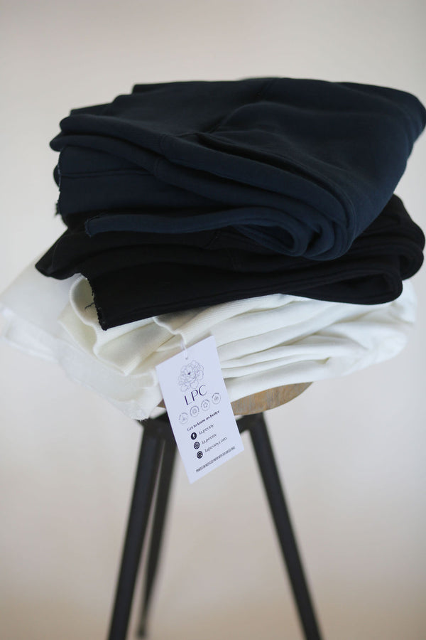 three stretch pants folded on a stool in white black and blue