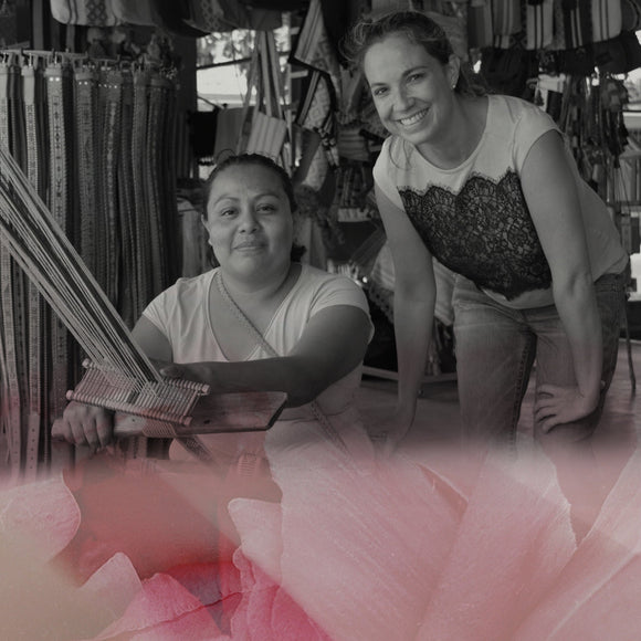 Woman standing next to another woman who is weaving silk