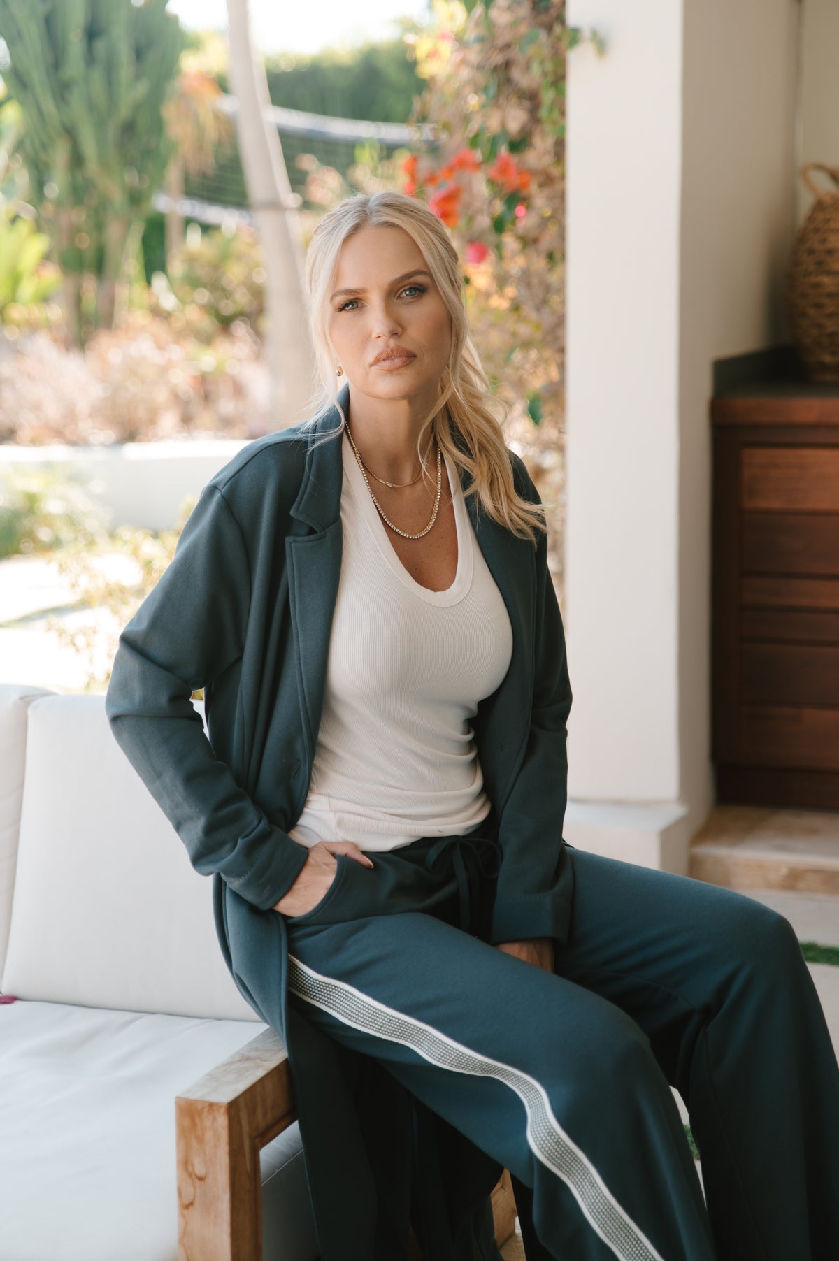 Woman sitting outdoors wearing a dark grey coat and pants and a white shirt