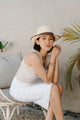 woman wearing tan tank top with long white skirt and tan fedora