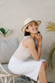woman wearing tan tank top with long white skirt and tan fedora