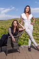 two women, one wearing white hooded jumpsuit, the other wearing black hooded jumpsuit