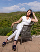 woman wearing white sleeveless shirt with gold zipper, with white pants